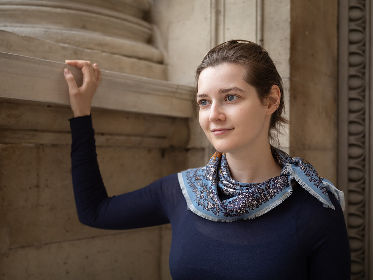 young lady wearing blue silk scarf with dragonfly motif and a black pull over