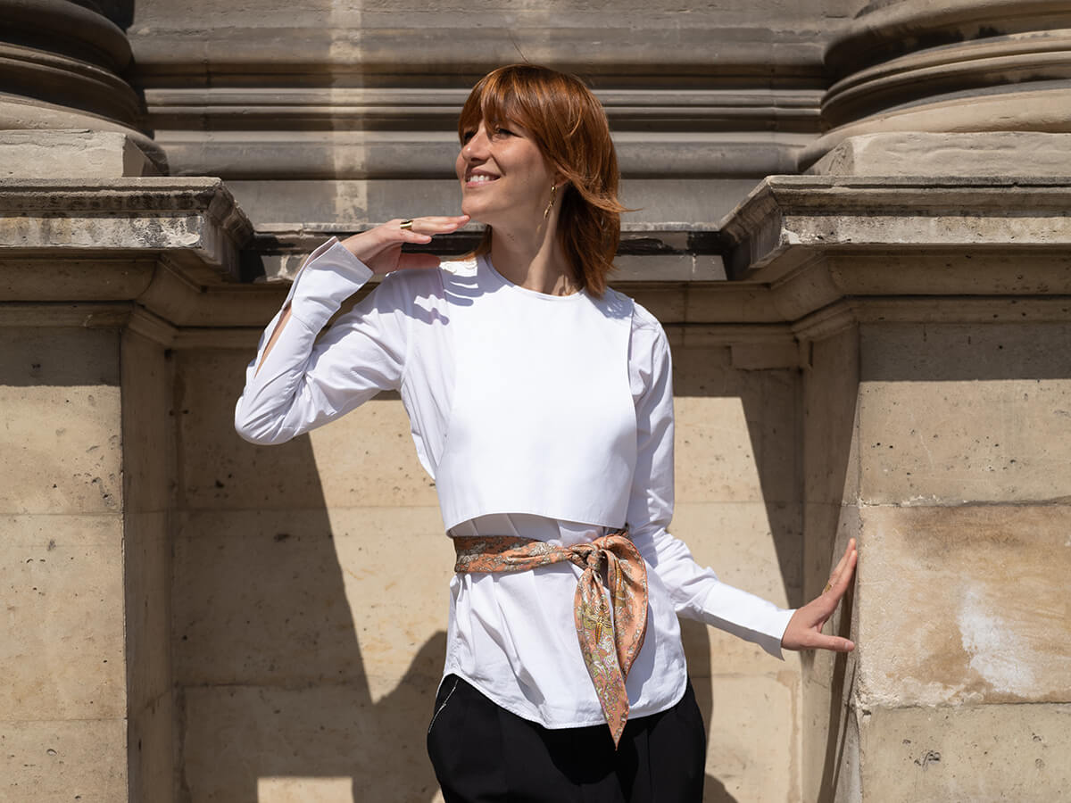 red hair young lady wearing a white shirt and a pink silk scarf with dragonfly motif around her waist