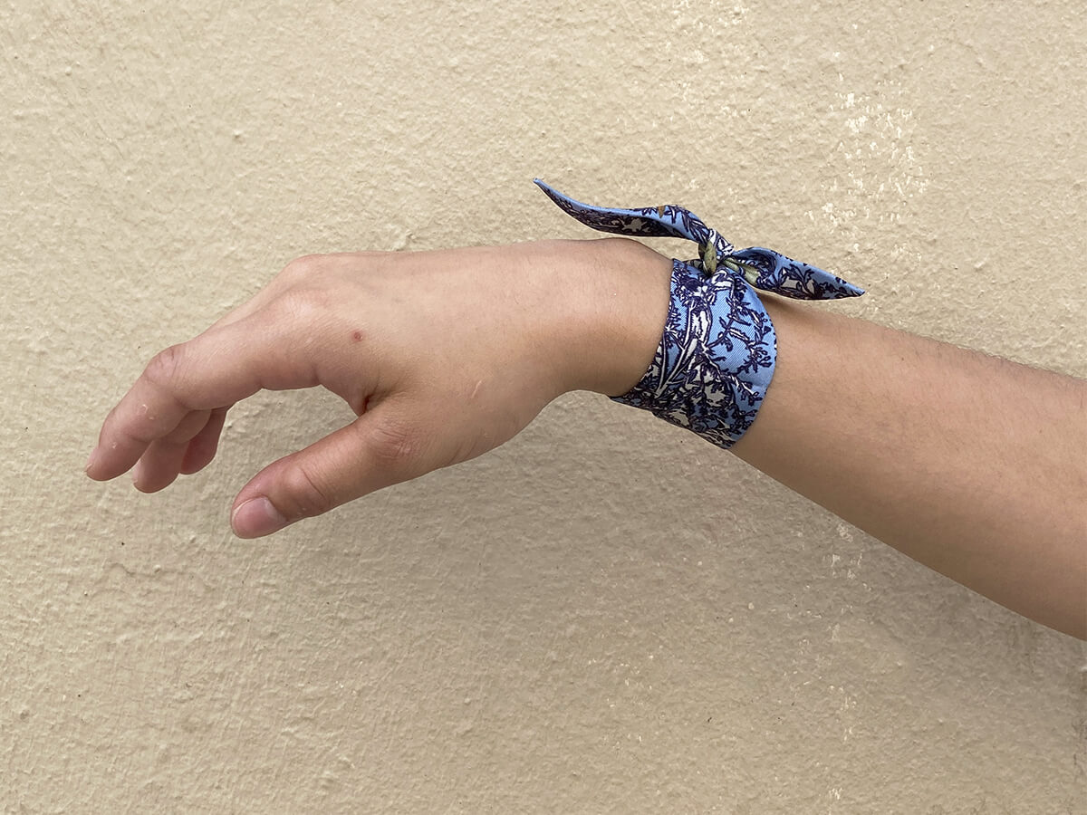 hand with a blue silk ruban with dragonfly motif around the wrist