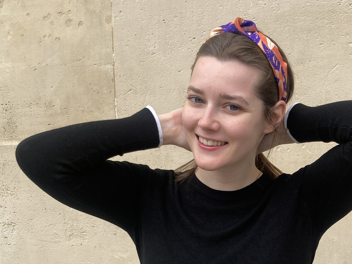 young lady wearing blue silk hairband with algae motif and a black pull over