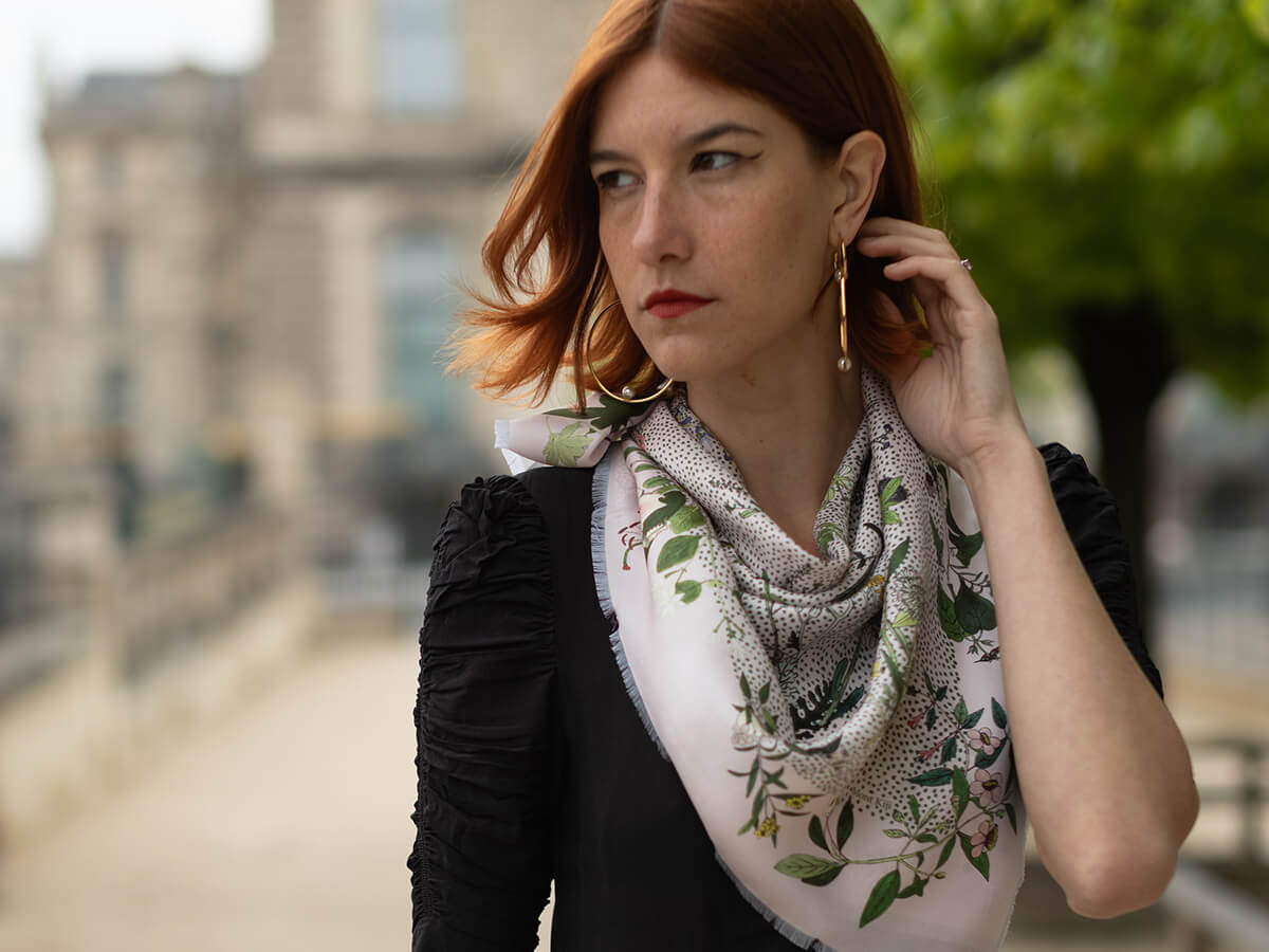 young lady wearing pink silk scarf with flower motif and a black pull over